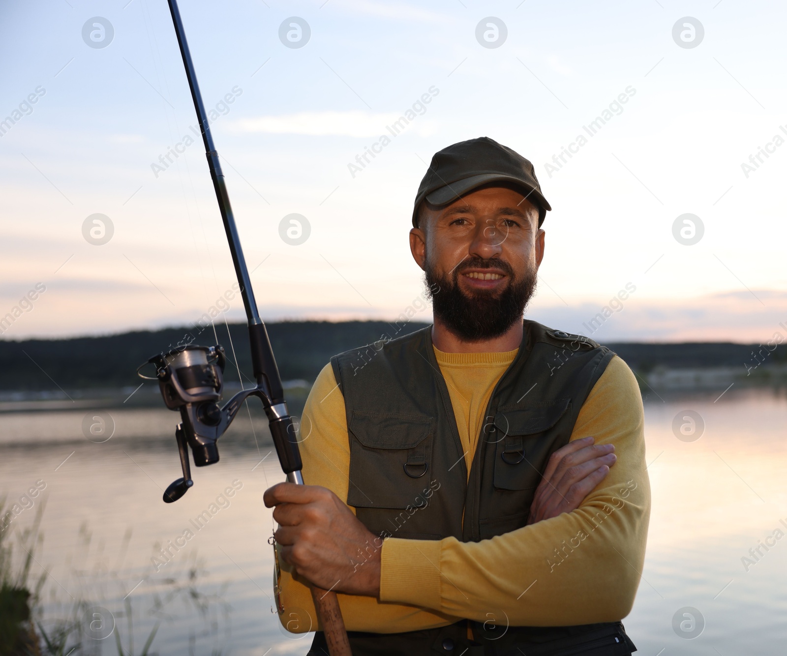 Fisherman with rod fishing near lake at sunset Photo of Fisherman with rod fishing near lake at sunset