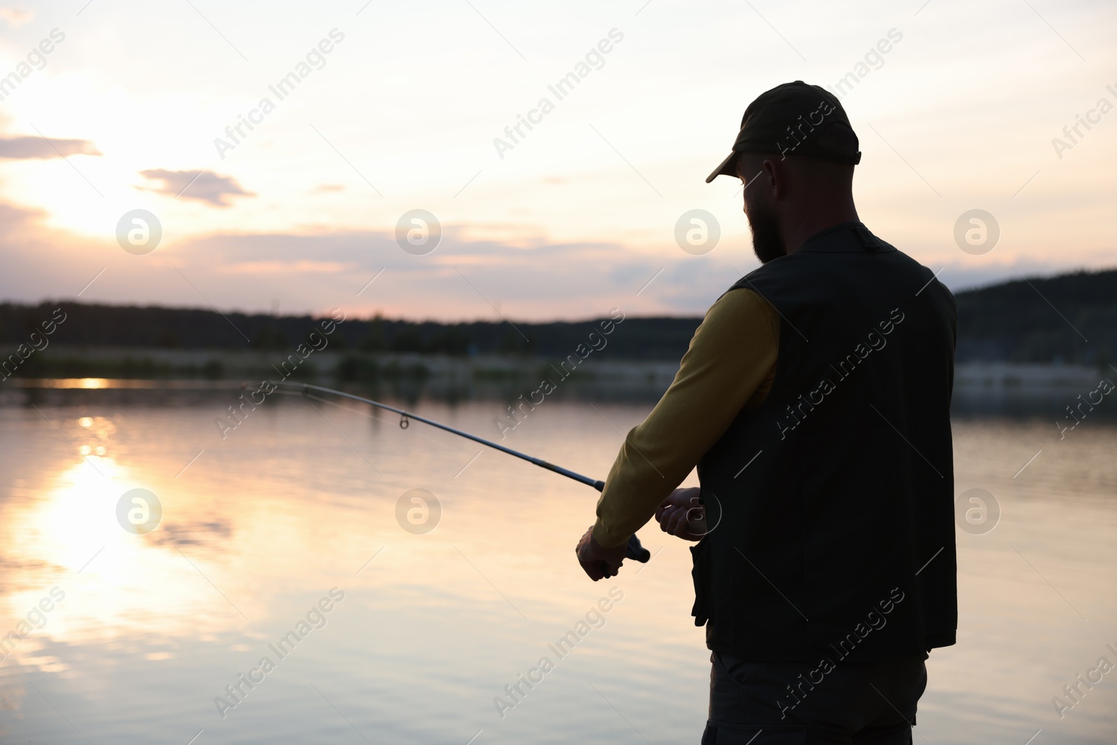 Fisherman with rod fishing near lake at sunset Photo of Fisherman with rod fishing near lake at sunset