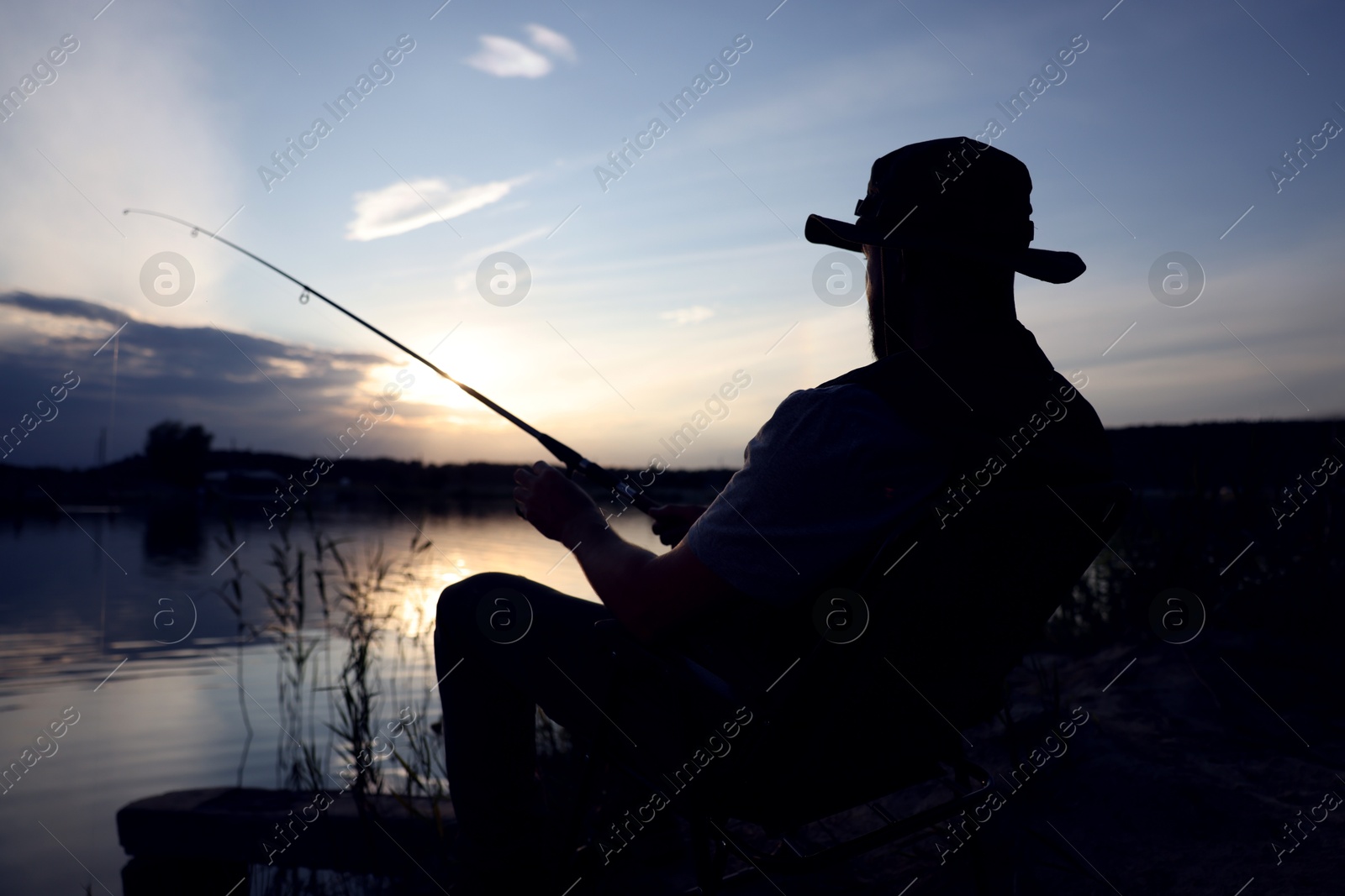 Fisherman with rod fishing near lake at sunset Photo of Fisherman with rod fishing near lake at sunset