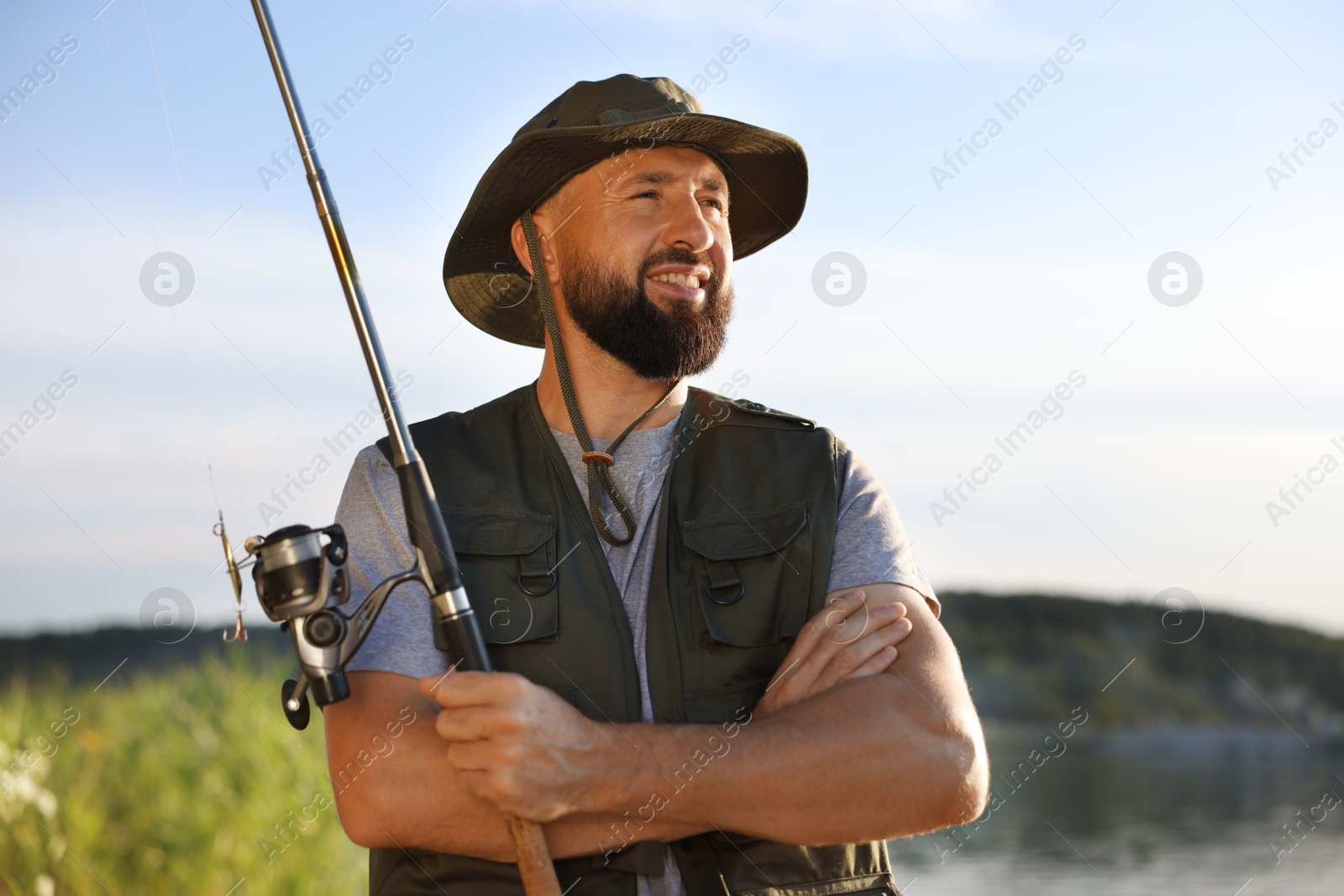Smiling fisherman with rod near lake at summer Photo of Smiling fisherman with rod near lake at summer