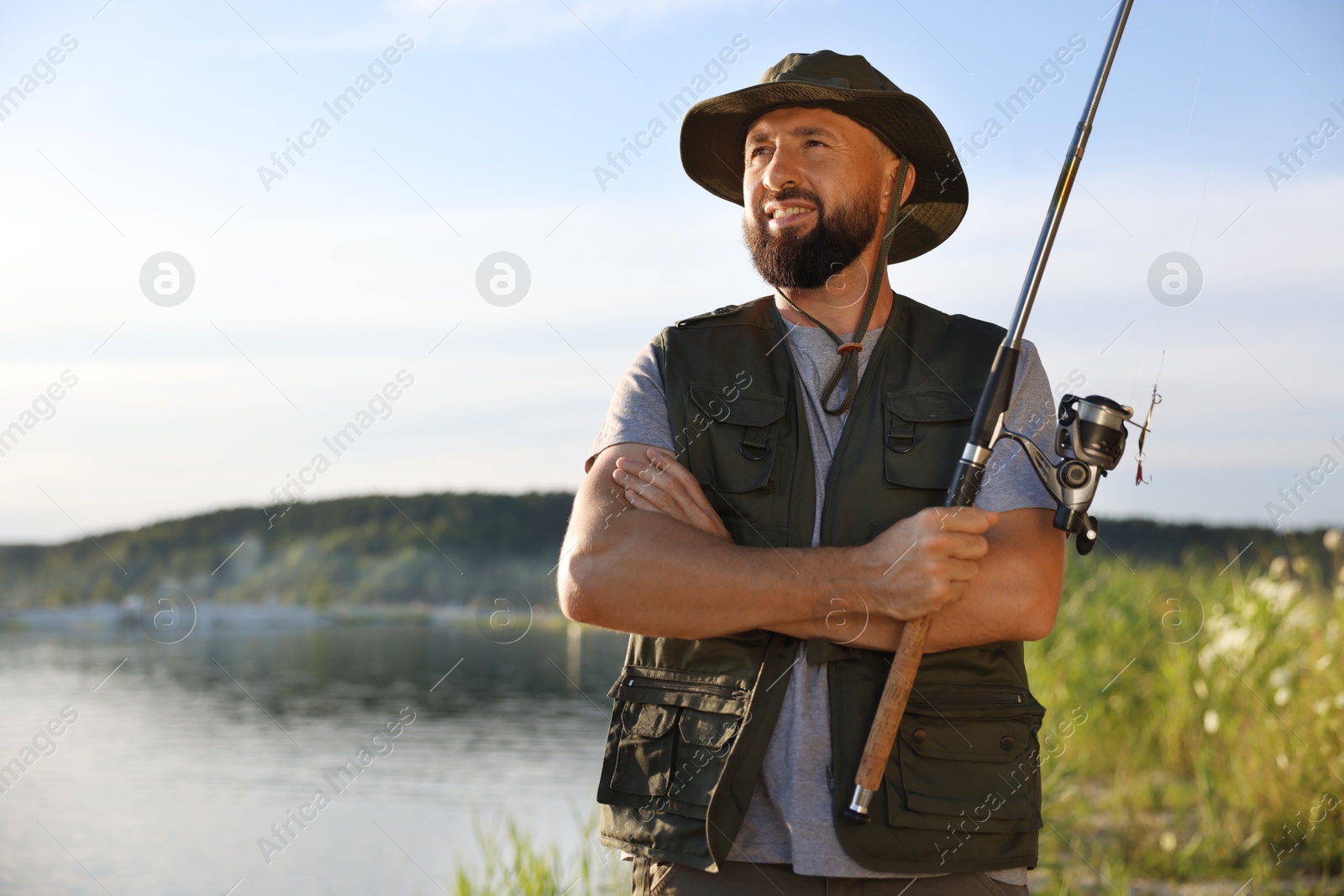 Smiling fisherman with rod near lake at summer Photo of Smiling fisherman with rod near lake at summer