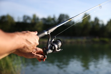 Photo of Fisherman with rod fishing near lake at summer, closeup