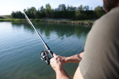Photo of Fisherman with rod fishing near lake at summer, closeup