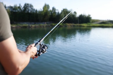 Photo of Fisherman with rod fishing near lake at summer, closeup