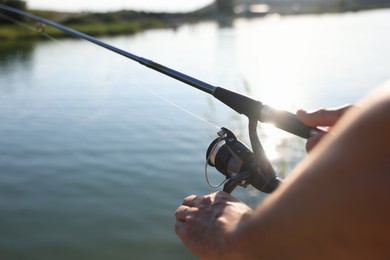 Photo of Fisherman with rod fishing near lake at summer, closeup
