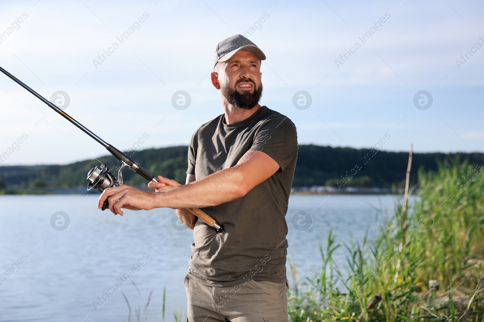 Smiling fisherman with rod near lake at summer Photo of Smiling fisherman with rod near lake at summer