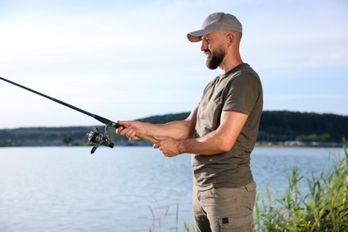 Photo of Fisherman with rod fishing near lake at summer