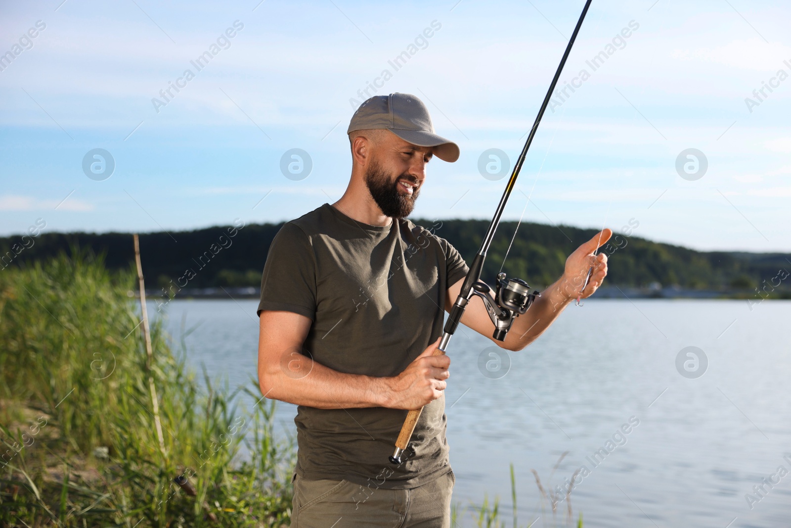 Smiling fisherman with rod near lake at summer Photo of Smiling fisherman with rod near lake at summer