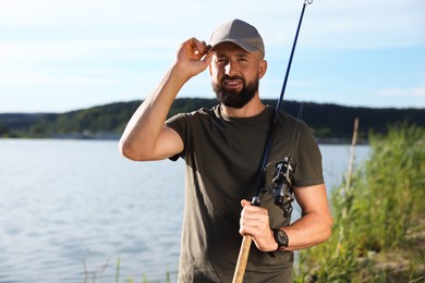 Photo of Fisherman with rod near lake at summer