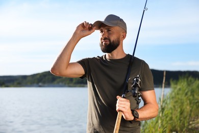 Photo of Fisherman with rod near lake at summer