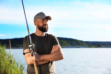 Photo of Fisherman with rod near lake at summer. Space for text