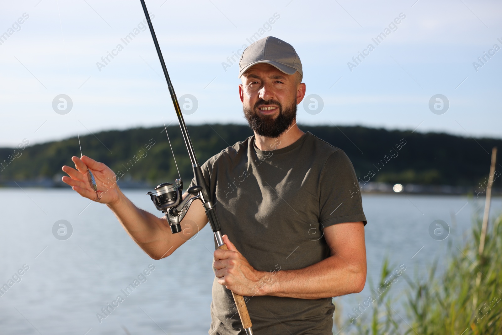 Smiling fisherman with rod near lake at summer Photo of Smiling fisherman with rod near lake at summer