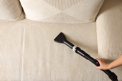 Photo of Woman cleaning sofa with vacuum cleaner, top view. Space for text