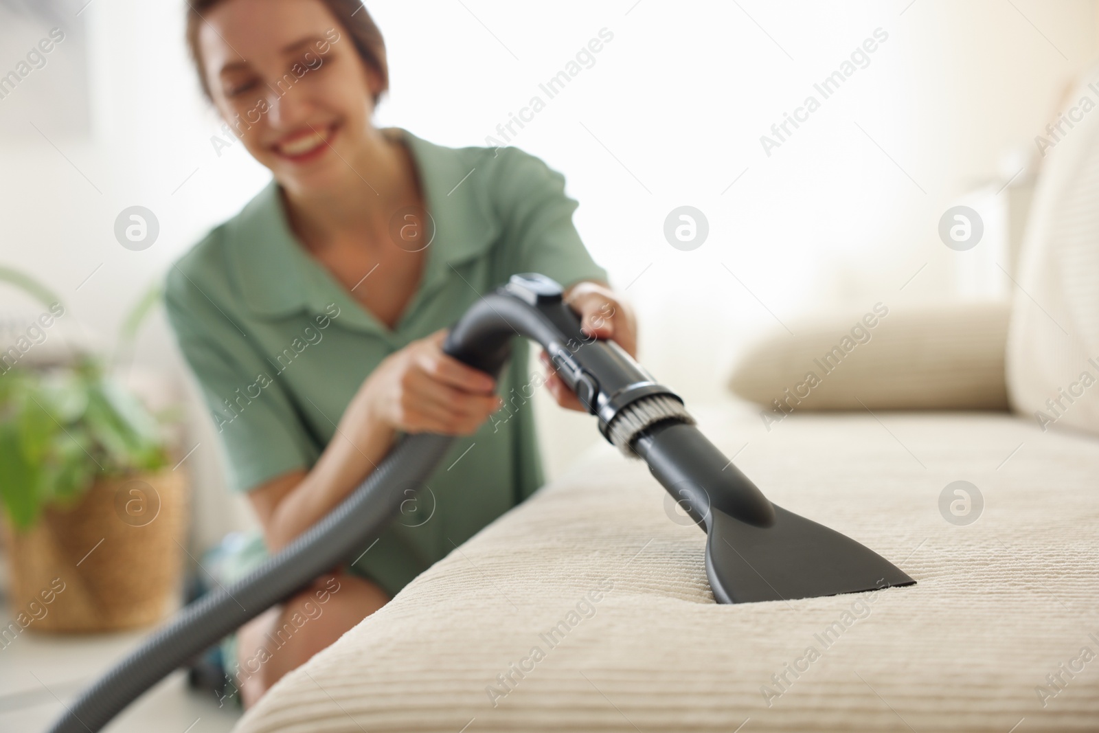 Woman cleaning sofa with vacuum cleaner at home, selective focus Photo of Woman cleaning sofa with vacuum cleaner at home, selective focus