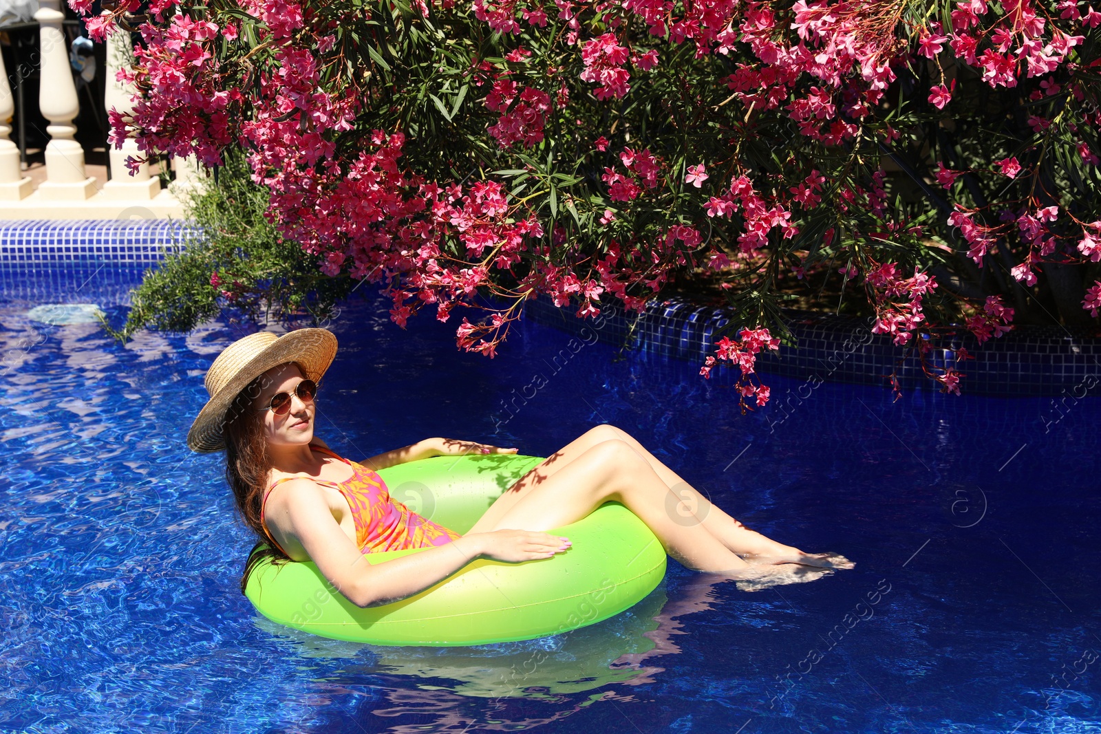 Photo of Girl on inflatable ring in swimming pool outdoors on sunny day