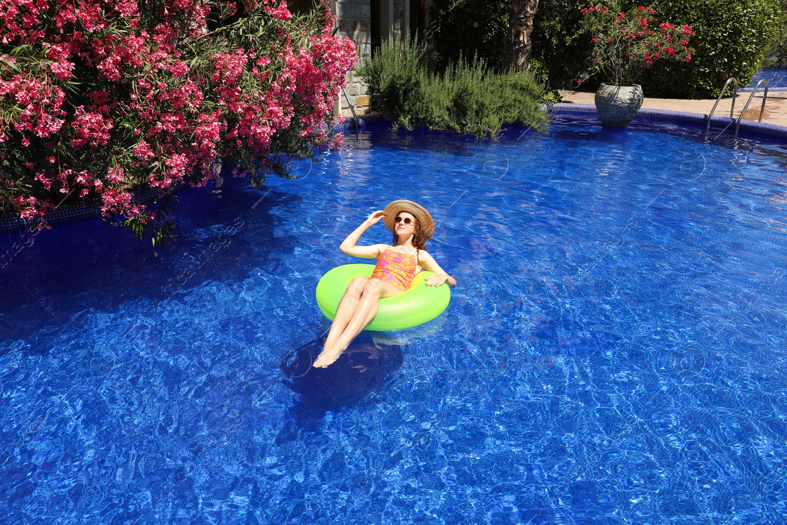 Photo of Girl on inflatable ring in swimming pool outdoors on sunny day, space for text