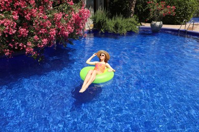 Photo of Girl on inflatable ring in swimming pool outdoors on sunny day, space for text