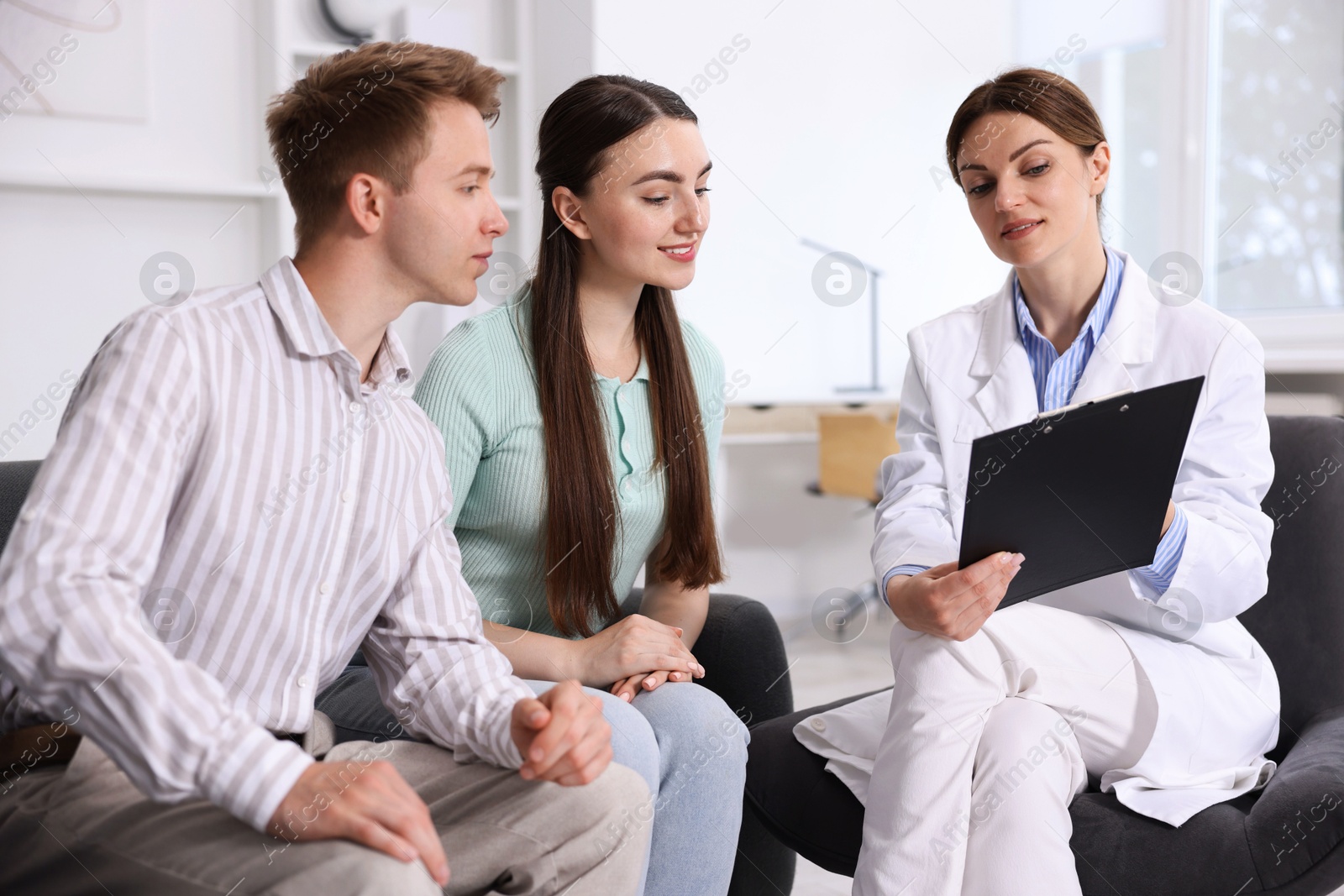 In vitro fertilization (IVF). Happy couple having appointment with doctor in reproductive clinic Photo of In vitro fertilization (IVF). Happy couple having appointment with doctor in reproductive clinic
