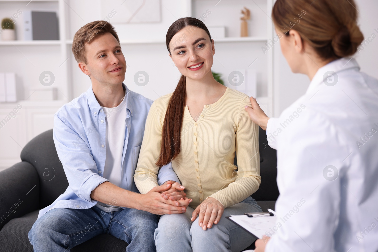 In vitro fertilization (IVF). Doctor encouraging couple during visit in reproductive clinic Photo of In vitro fertilization (IVF). Doctor encouraging couple during visit in reproductive clinic