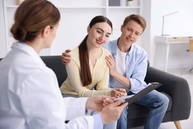 Photo of In vitro fertilization (IVF). Happy couple having appointment with doctor in reproductive clinic