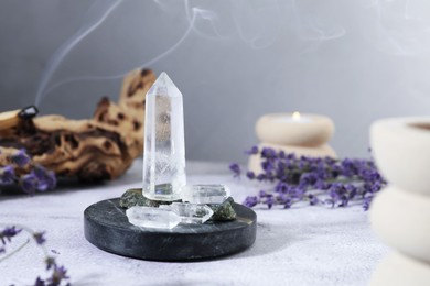 Photo of Aura. Different crystals, lavender, burning candle and Palo Santo on white textured table, closeup