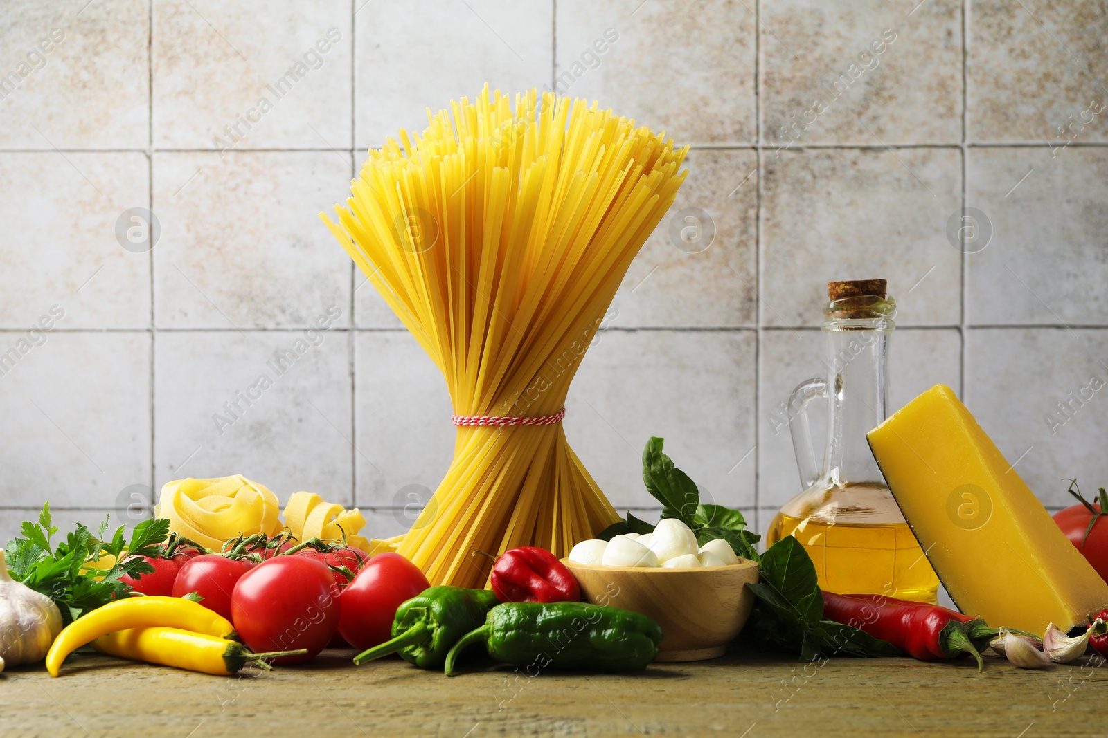 Photo of Different types of pasta and ingredients on wooden table