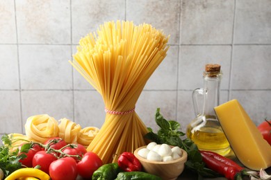 Photo of Different types of pasta and ingredients on table, closeup