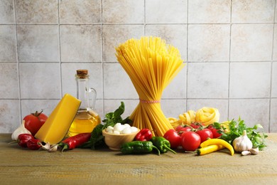Photo of Different types of pasta and ingredients on wooden table