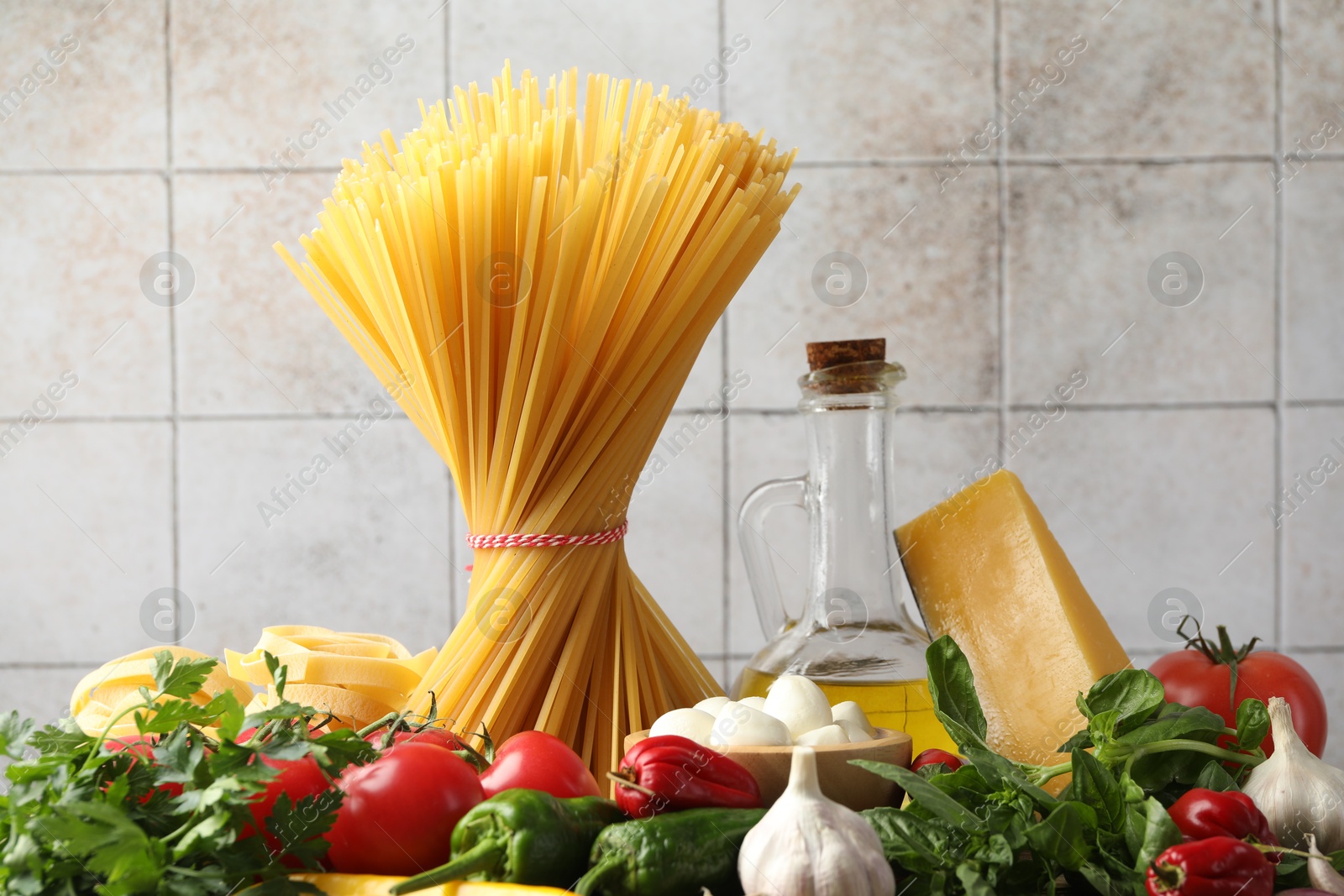 Photo of Different types of pasta and ingredients on table, closeup