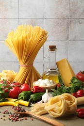 Photo of Different types of pasta and ingredients on wooden table, closeup