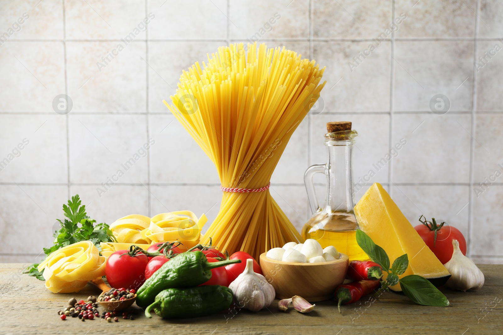 Photo of Different types of pasta and ingredients on wooden table