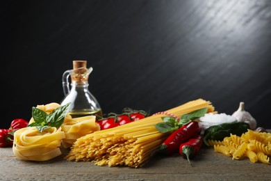 Photo of Different types of pasta and ingredients on wooden table, closeup