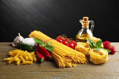 Photo of Different types of pasta and ingredients on wooden table