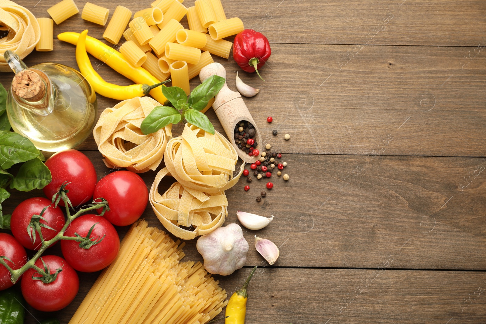 Photo of Different types of raw pasta and products on wooden table, flat lay. Space for text