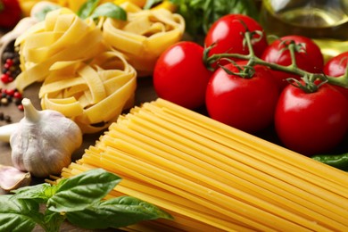 Photo of Different types of raw pasta and products on table, closeup