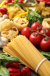 Photo of Different types of raw pasta and products on table, closeup