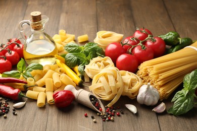 Photo of Different types of raw pasta, products and spices on wooden table, closeup