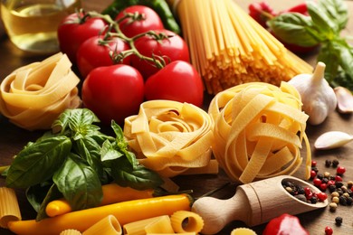 Photo of Different types of raw pasta, products and spices on wooden table, closeup