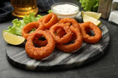 Photo of Fried squid rings served with sauce on black table, closeup