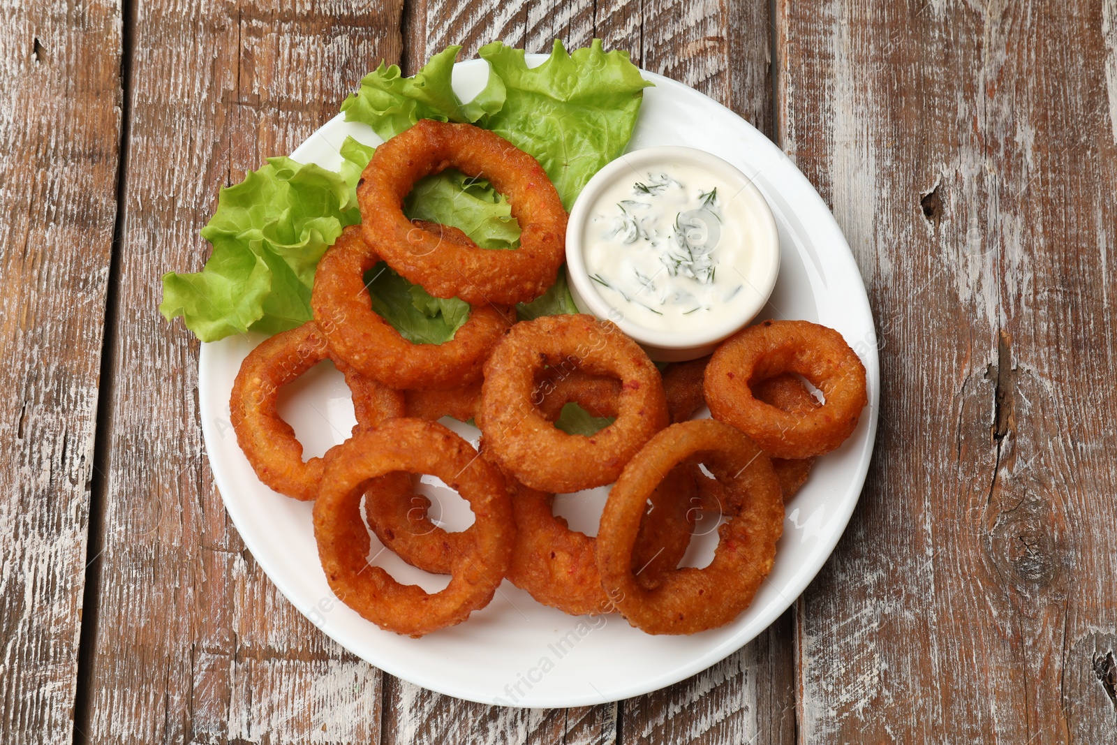 Fried squid rings served with sauce on wooden table, top view Photo of Fried squid rings served with sauce on wooden table, top view
