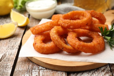Photo of Fried squid rings served with sauce on wooden table, closeup