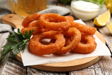 Photo of Fried squid rings served with sauce on wooden table, closeup