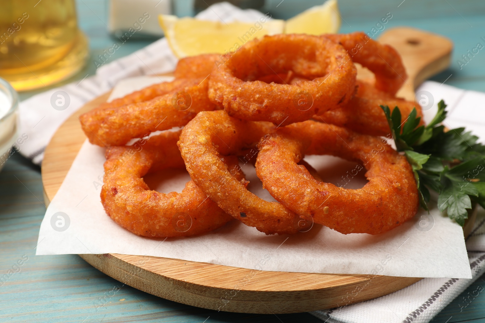 Fried squid rings, parsley and lemon on light blue wooden table, closeup Photo of Fried squid rings, parsley and lemon on light blue wooden table, closeup