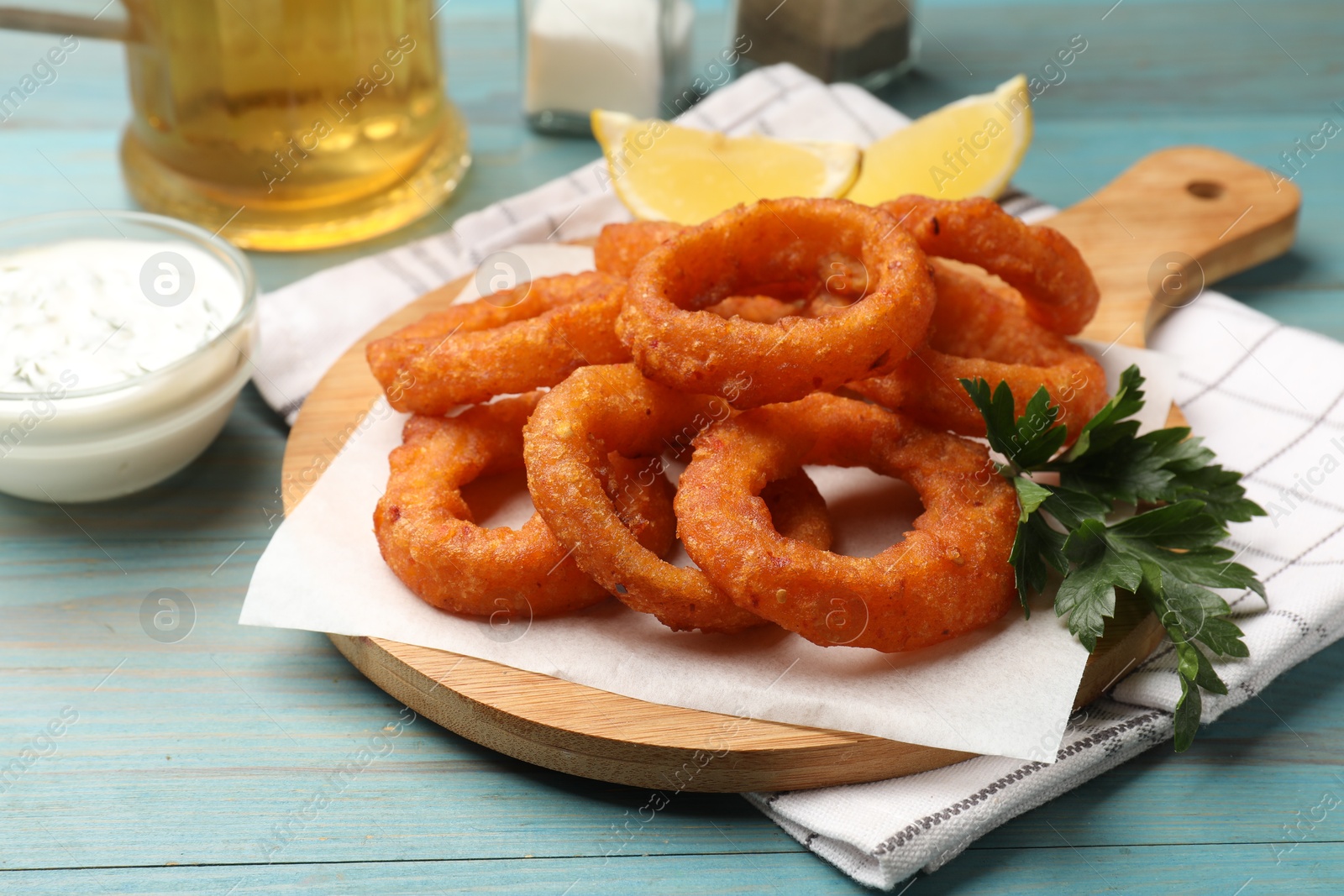 Fried squid rings served on light blue wooden table, closeup Photo of Fried squid rings served on light blue wooden table, closeup