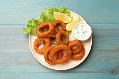 Photo of Fried squid rings served with sauce on light blue wooden table, top view