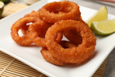 Photo of Fried squid rings and lime on table, closeup
