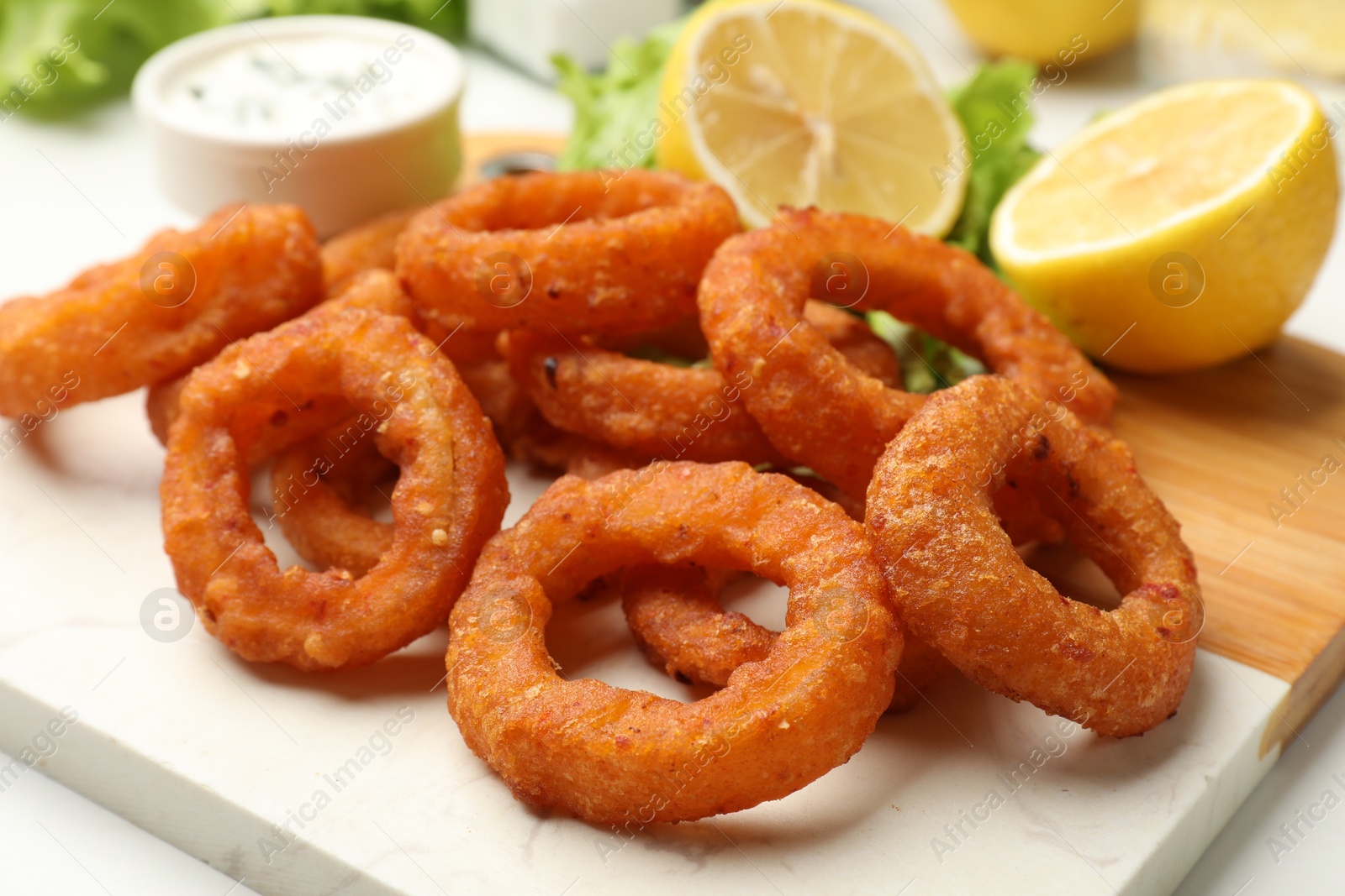 Fried squid rings served with sauce on table, closeup Photo of Fried squid rings served with sauce on table, closeup