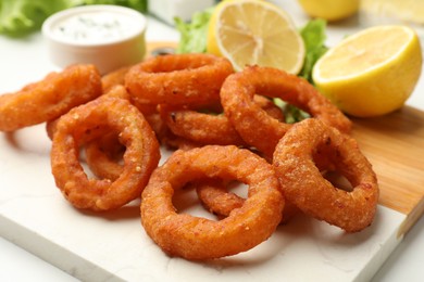 Photo of Fried squid rings served with sauce on table, closeup
