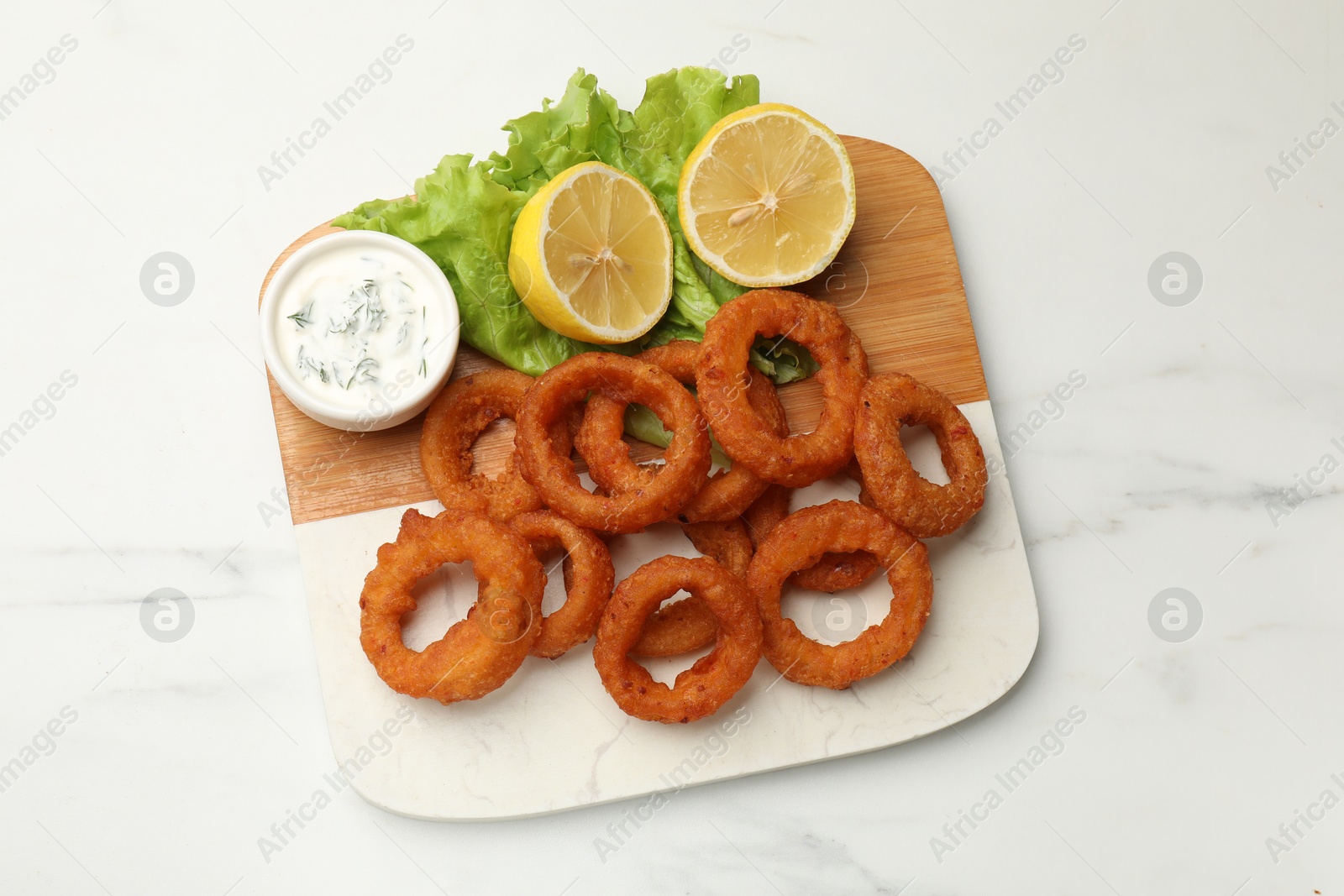 Fried squid rings served with sauce on white marble table, top view Photo of Fried squid rings served with sauce on white marble table, top view