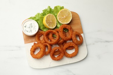 Photo of Fried squid rings served with sauce on white marble table, top view